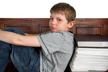 Gefrustreerde jongen zit met zijn rug tegen een stapel boeken