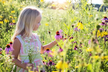 Meisje in een geel en roze bloemenveld