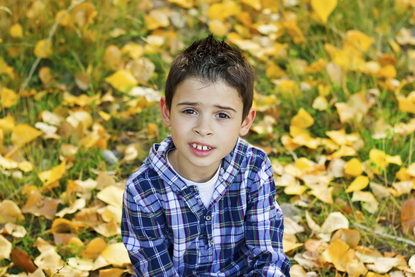 Jongetje in het gras met herfstbladeren